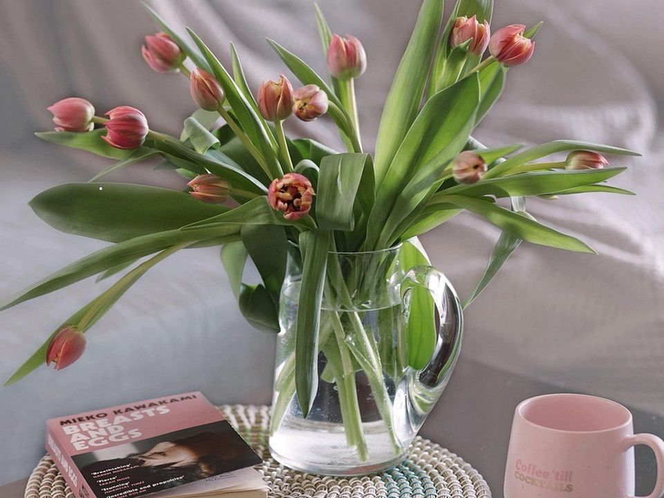 A vase of tulips and a coffee cup on a kitchen table