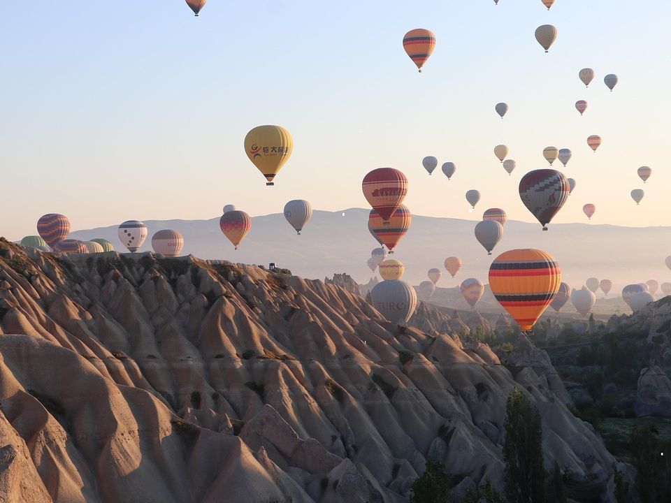 Hot air balloons rising over a valley at dawn